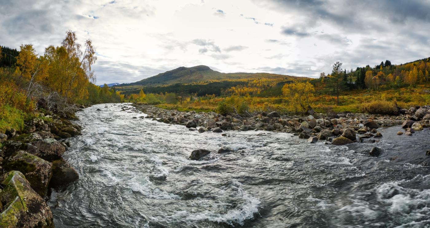 Bilde av ei elv, fjell i bakgrunnen