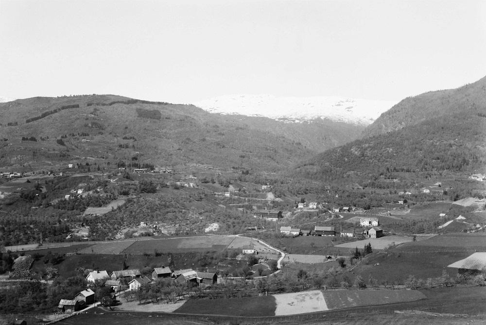 Eit oversiktsfoto frå tidlegare tid, teke av Håkon Njøs. Her ser me skulestova og landskapet omkring. Me ser gardane på Nedre Njøs og i Gjerdet. I bakgrunnen ligg Henja, Røysa og Dalen.