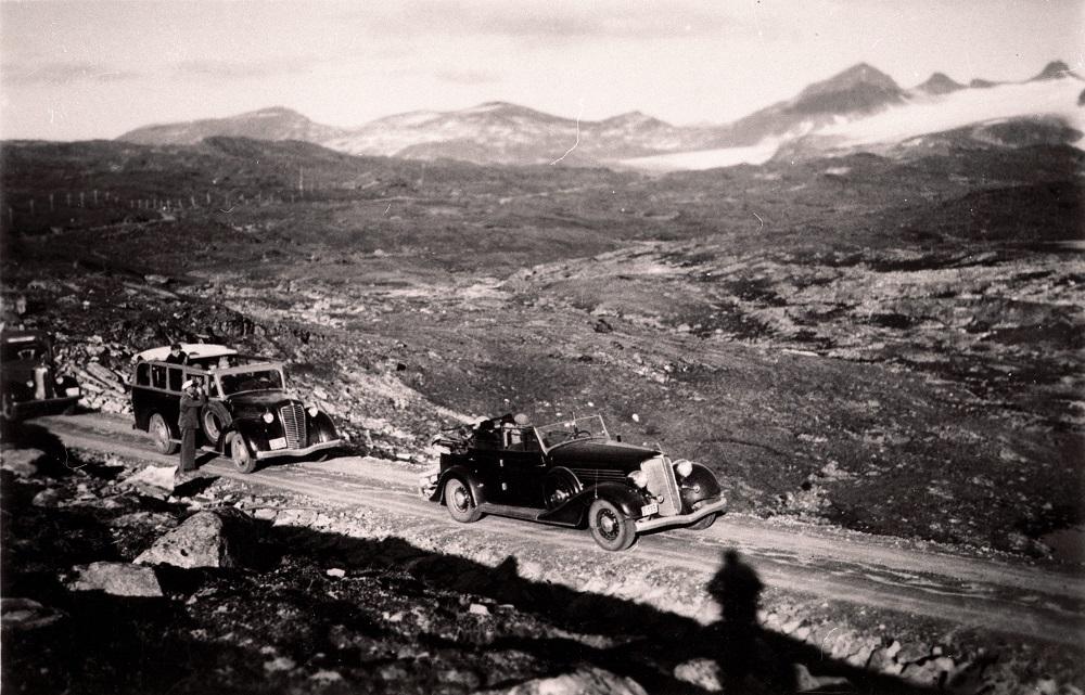 Biletet er frå Sognefjellsvegen sine første dagar. Her er det turkøyring med opne rutevogner. Vegdekket var grus, og køyrebreidda veksla frå 3 m i kostbart terreng til 5 m på parti der ein auke i vegbreidda ikkje påverka kostnadene. I ein kommentar til vegstandarden seier Sogns Avis i 1938, at nedanfor Turtagrø var det eit stykke av vegen som ikkje var vidare godt å køyra, men at det likevel ikkje var verre enn at bilane kunne komma fram. Dette partiet vart utbetra i 1939.
