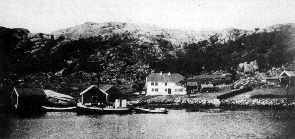 Sommar og slåttonn i Rånøy kring 1935. Frå høgre ser me løa og fjøsen, med ei tilbygd sval for lam og sauer. Eldhuset med gråsteinsgrue og det velinnreidde stabburet var nødvendige for den daglege drifta. Det store bustadhuset vart påbygt og fekk denne vakre forma i 1874. I naustet stod notbåtar og færingar som ikkje var i dagleg bruk. Sjøbua, der ein salta og tok vare på fisk og sild, vender gavlen mot hamna. På skjåen (påbygd seinare) låg nøtene og her vølte dei notbruk og teiner. Skøyta, og notbå...