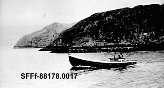 Her ser me ein typisk motorbåt kosta for småfiske, han var seint og tidleg på feltet med påtetroene. Karl Storøy er på veg ut til fiskeplassane. Båten vart bygd i 1934 og har Sabb-motor. Det var vanleg å byggje ruff over motoren slik som på biletet. Framfor ruffen låg fiskebrønnen med luker over. Når ein opna ventilane og sjøen strøymde inn i brønnen, var båten nokolunde 1/3 lasta.