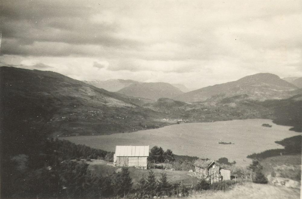 Steigastølen med Hafslovatnet og Hafslobygda i bakgrunnen. Nyaselet, bygt i 1940, til venstre, og det monaleg mindre Gamlaselet. Til høgre i biletet syner litt av den oppdyrka slåtteteigen, <i>slåttegjerdet.</i> Teigen har namnet Strandagjerdet.