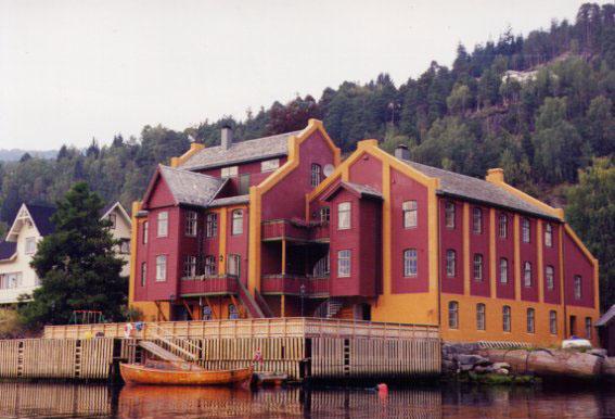 I dag er den gamle mølla eit staseleg bygg. Biletet er teke frå same vinkel som biletet til venstre. Framfor bygningen ser vi den rommelege kaia, som er "hagen" til dei tre familiane som bur i huset. Vekslinga mellom raud og okergul farge framhevar lisenearkitekturen.
