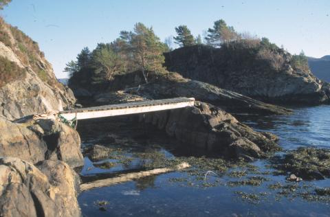 Frå fastlandssida er det bygd ei treklopp over til holmen midt i sundet, der blåsteinskaret ligg.