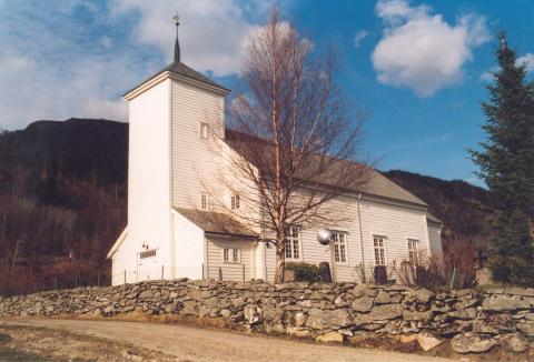 Vevring kyrkje. Minnesteinen på grava til Anders Redal er såvidt synleg til høgre for bjørka, under lyskjelda.