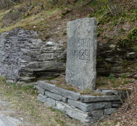 Grensestein mellom kommunane Innvik og Stryn attmed vegen mellom Stryn og Faleide. Årstalet 1891 står truleg for året det kom køyreveg mellom Stryn og Faleide (til hovudvegen Faleide – Hellesylt).