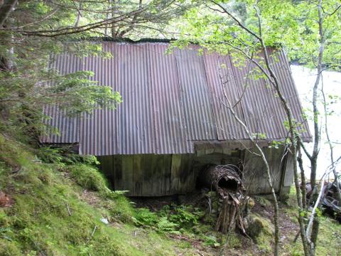 "oppført av standerverk, har panelte vegger og  byljeblekk på taket" (i branntakst 1946). Me ser ein rest av røyrgata som går inn i kraftverkshuset til turbinen