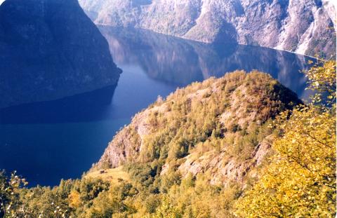 Heimebøen på Horten med fjellet Beitelen i bakgrunnen. På bøen er restane etter to høyløer. Nedanfor bøen er det eit høgt, bratt berg. 