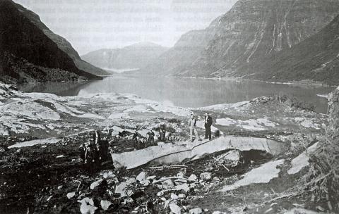 Vraket av "Lodalen" kort tid etter raset 13. september 1936. Båten vart kasta 400 m innover land på Nesodden av flodbølgja etter raset 14. januar 1905. Han låg då i vinteropplag i ei vik rett over frå rasstaden, utanom biletet til venstre. Flodbølgja etter raset i 1936 kasta vraket endå lenger inn på land og høgare opp. Biletet syner vatnet nord-vestover mot Vassenden. Gardane på nordsida er Helset og Hogrenning.