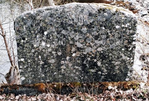 Denne grensesteinen står ved Årøyelva, like sør for den vesle tunnellen Hafslovatnet. Han markerte i si tid kommunegrensa mellom Sogndal og Hafslo kommune, no mellom Sogndal og Luster. 1904 var året vegen på vestsida av Årøyelva ferdig hit. Den nye vegstrekninga var ferdig i 1905.
