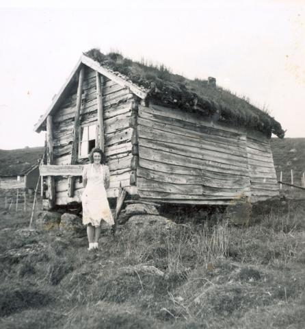 bilde av kvinne foran gamalt gardshus