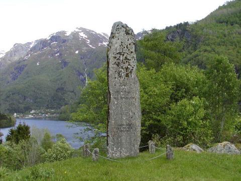 Øvst på steinen er innhogge ein latinsk kross. I midten står: MINNE OM HYEKYRKJA I MILLOMALDEREN. Nede står: GUDS ORD DET ER VÅR FEDRAARV. Rett ned frå steinen ligg <i>Kjerkjevikja.</i> I bakgrunnen Straumsholmen der ein i venstre biletkant skimtar kyrkja som vart vigsla i 1876.
