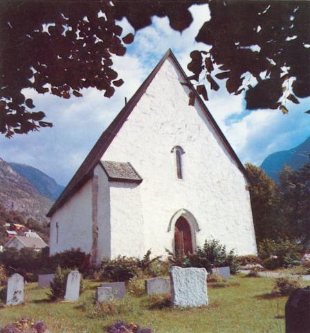 Vangen kyrkje i Aurland sett mot hovudinngangen mot vest. Fellesgrava markert med minnestein er på nordsida, utanfor biletkanten til venstre.
