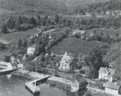 Huset framme midt i biletet er villaen som James Livesey bygde kring 1905. Me ser korleis huset, stranda og kaien danna ein viktig heilskap. Naustet høyrer òg til eigedommen og det var her Normann hadde den vakre båten sin. Han hadde òg ein vakker nordlandsbåt som var eit syn på Sognefjorden i stille sommardagar.